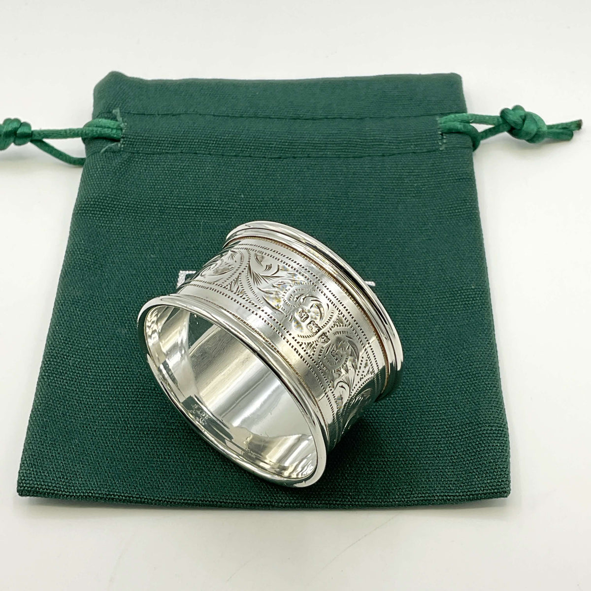 Back of Antique silver napkin ring on a green gift bag and white background 