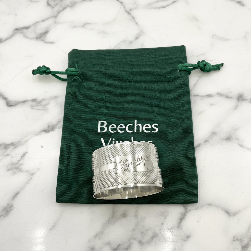 Silver napkin ring with Lynda on on the front on a gift bag on a marble background 