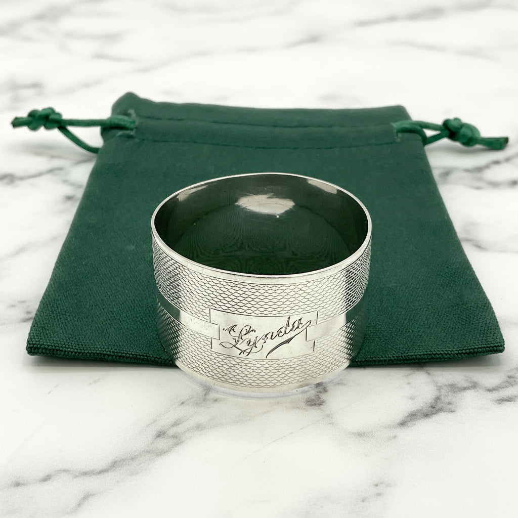 Silver napkin ring with Lynda on on the front on a gift bag on a white background 