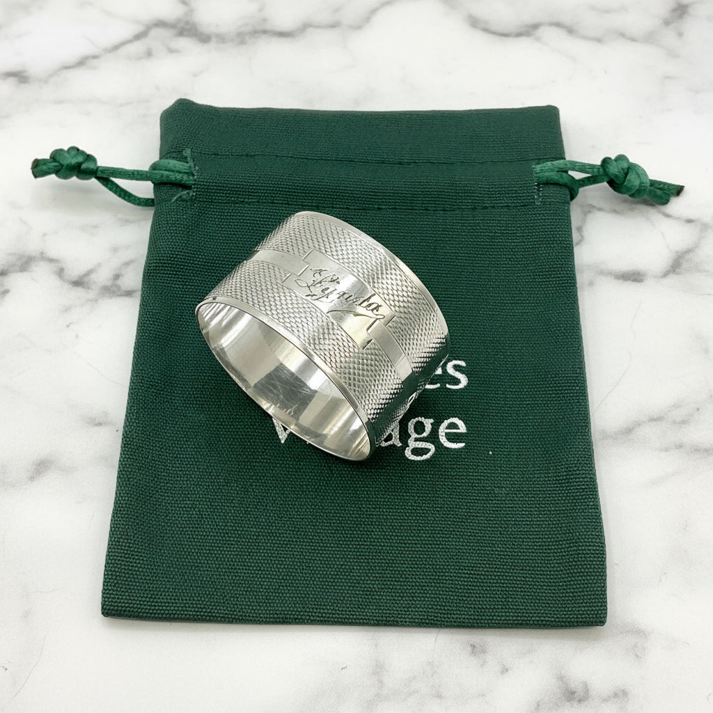 Silver napkin ring with Lynda on on the front on a gift bag on a marble background 