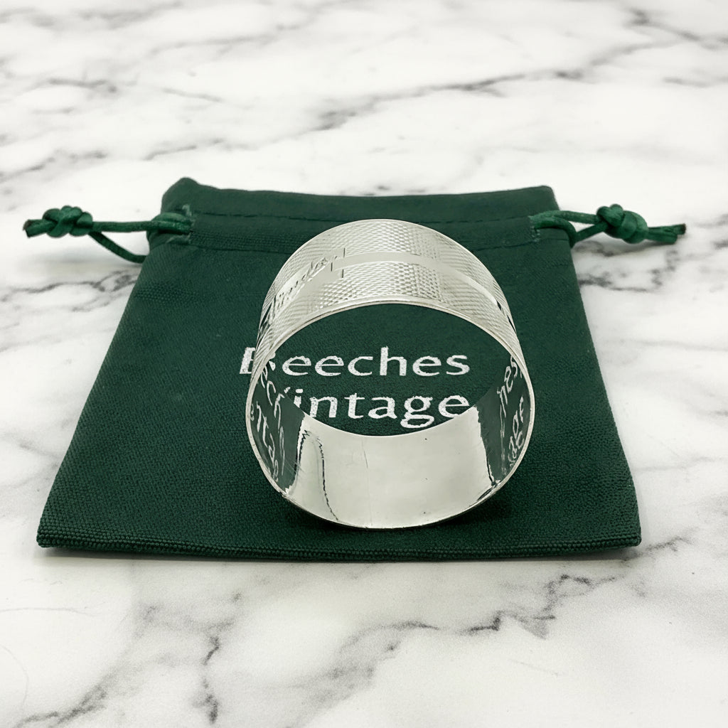 Silver napkin ring with Lynda on on the front on a gift bag on a marble background 