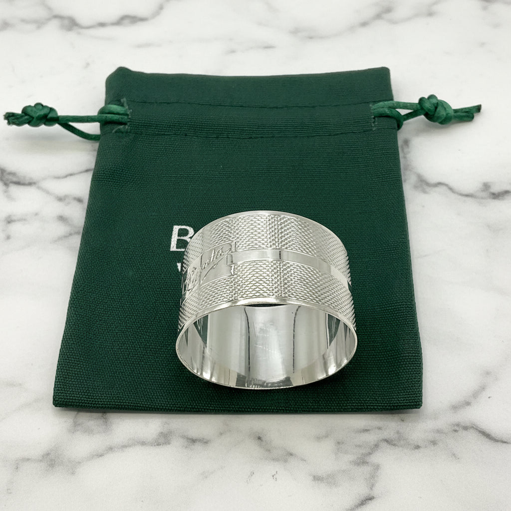 Silver napkin ring with Lynda on on the front on a gift bag on a marble background 