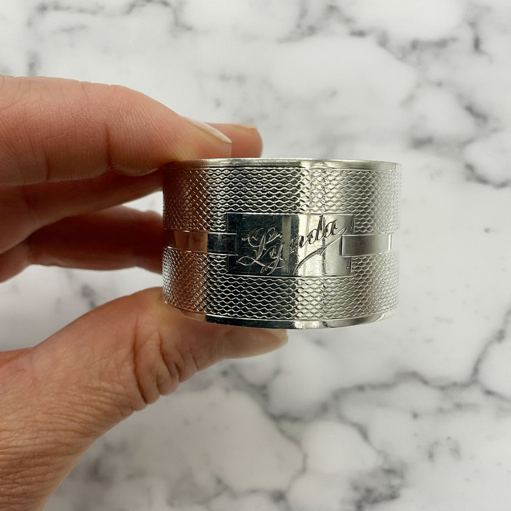 Silver napkin ring held in a hand with a marble background 