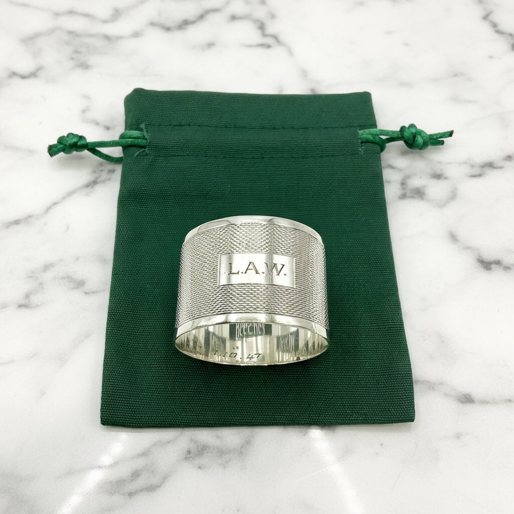 Silver napkin ring with LAW engraved on the front on a green gift bag and white background 