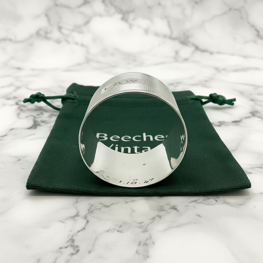 Inside of Silver napkin ring with LAW engraved on the front on a green gift bag and marble background 