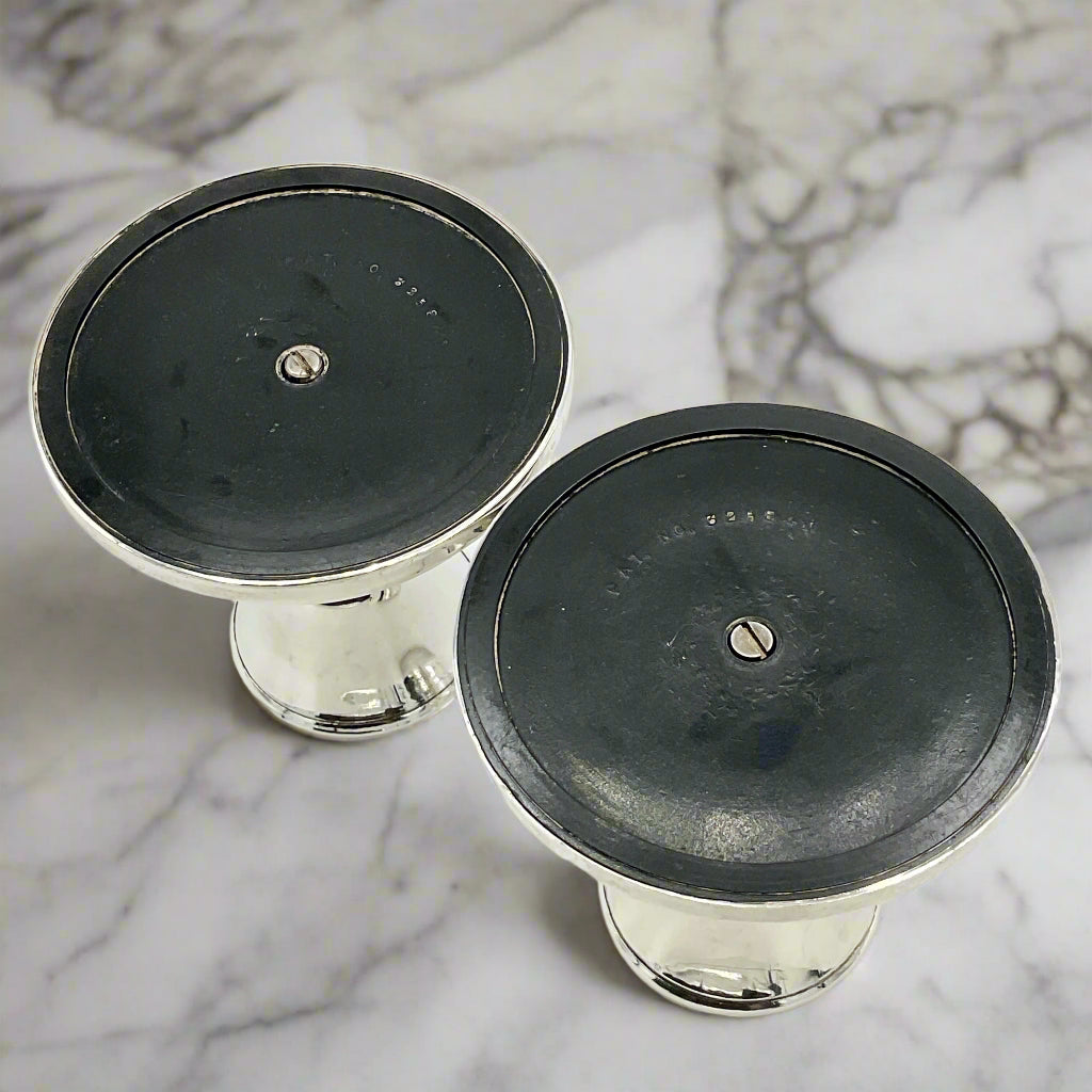 Two silver candle holders upside down on a marble worktop