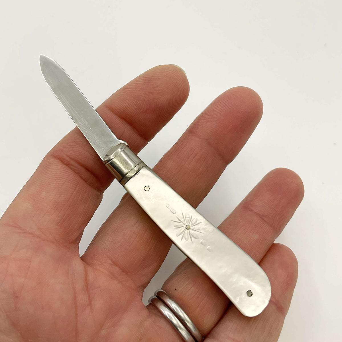 Silver fruit knife held in a hand with a white background 