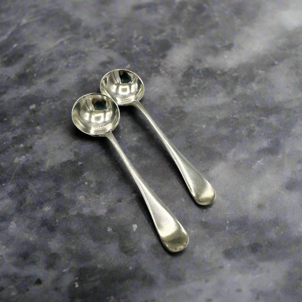 Two silver spoons on a gray stone surface