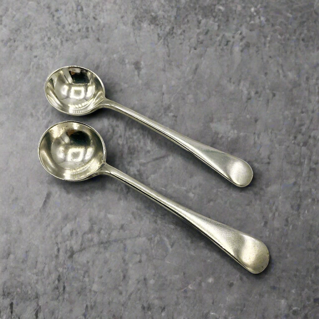 Two silver spoons on a light gray surface
