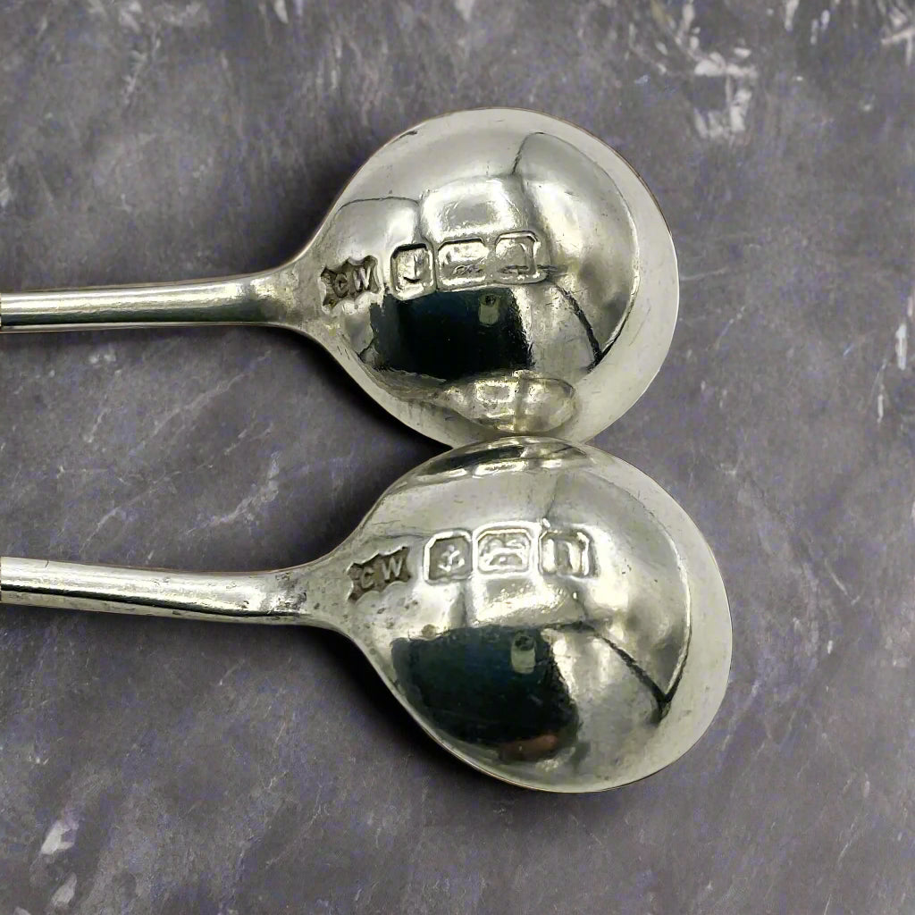 Two silver spoons showing hallmarks on a granite worktop 