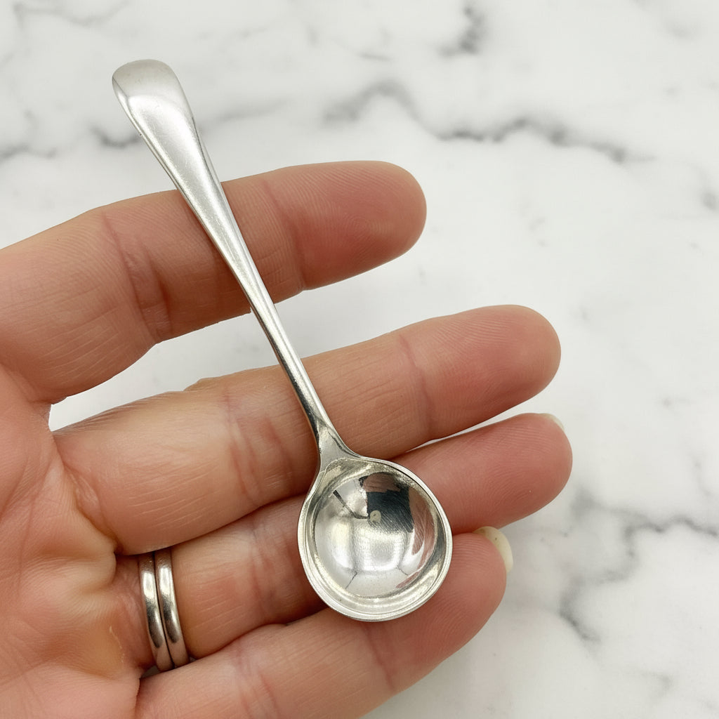 Silver spoon held in a hand against a marble background