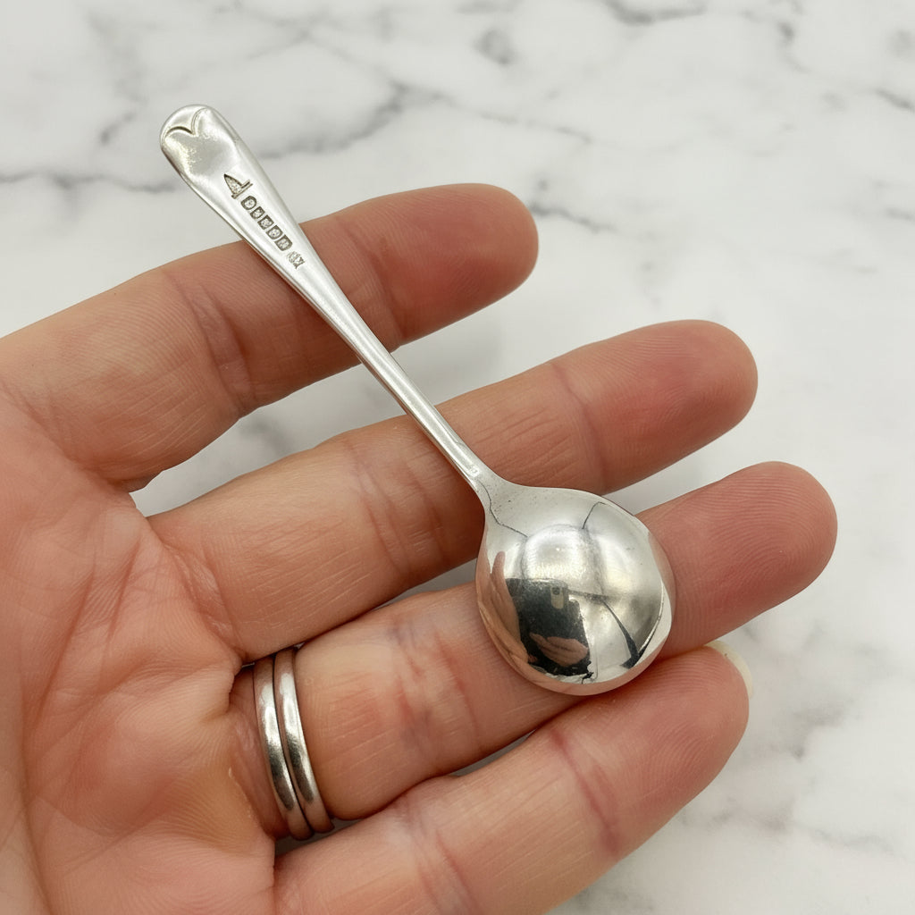 Silver spoon held in a hand with a marble background