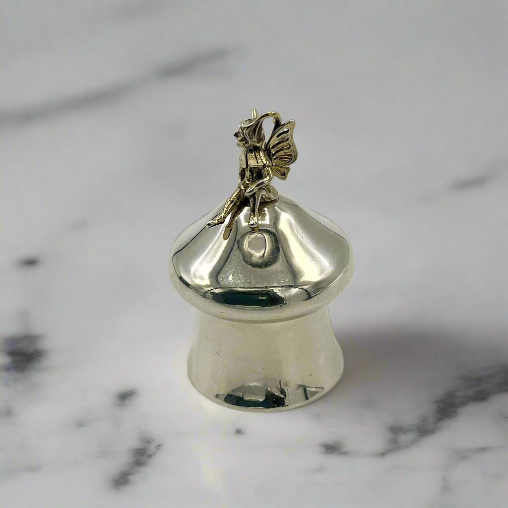 Silver pill box with fairy on top on a marble background