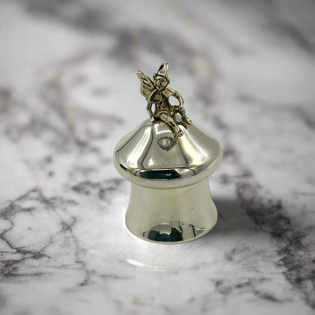 Silver bell with a fairy figurine on a marble surface