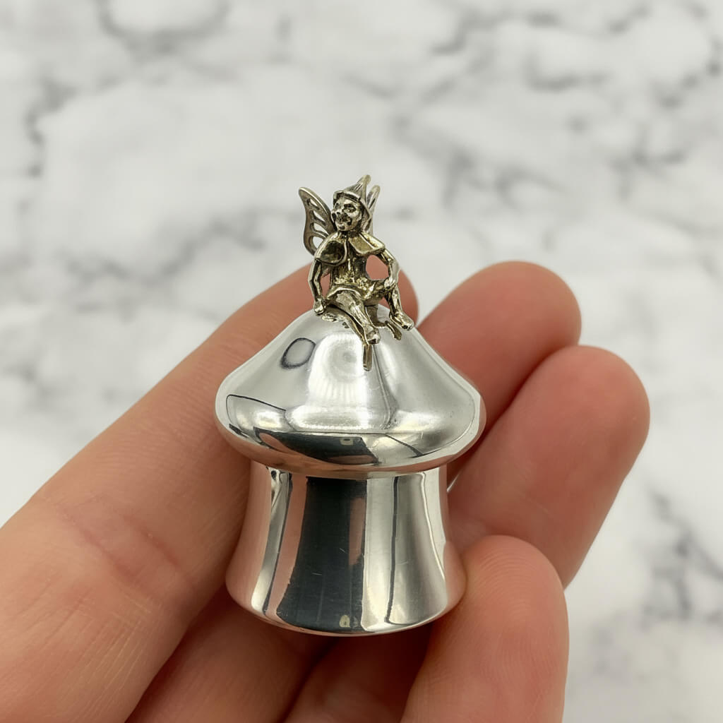 Silver fairy pill box held in a hand with a marble background