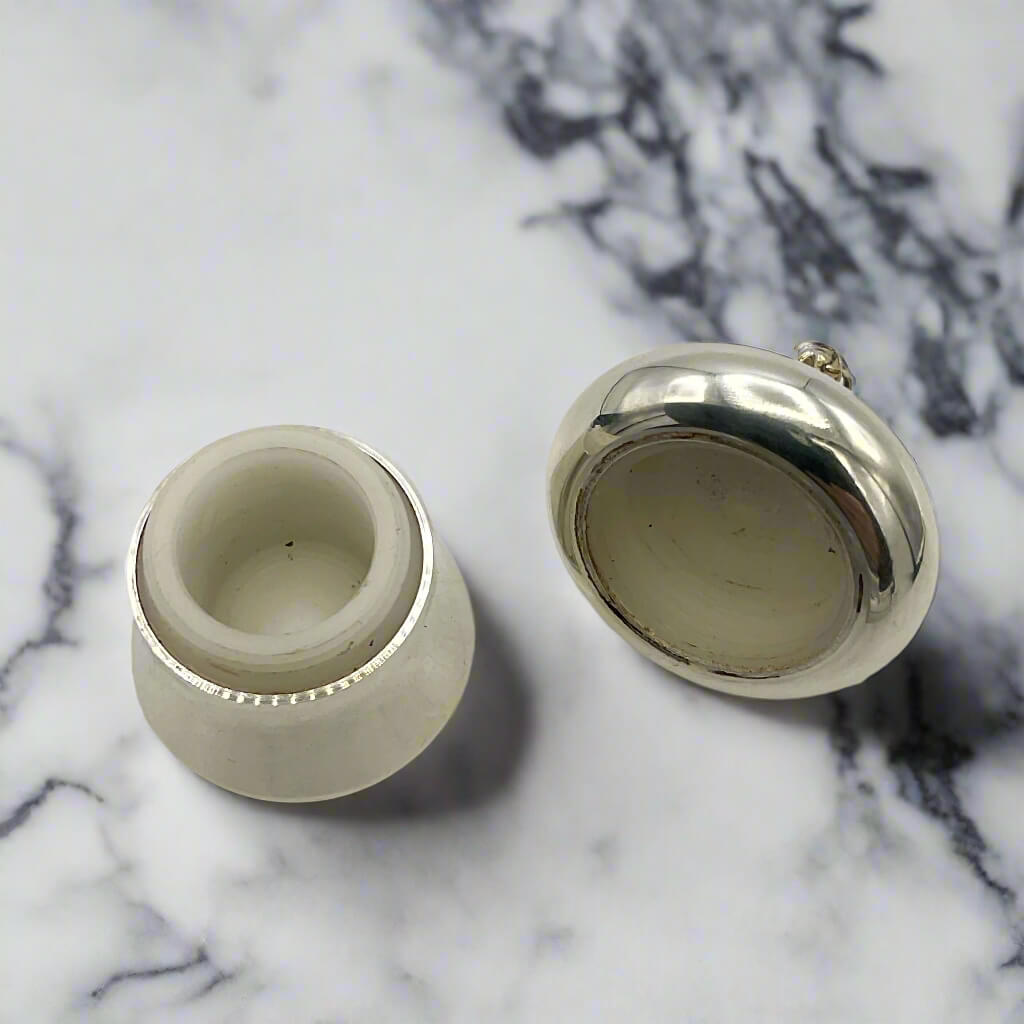 open eilver pill box showing plastic interior on a marble surface