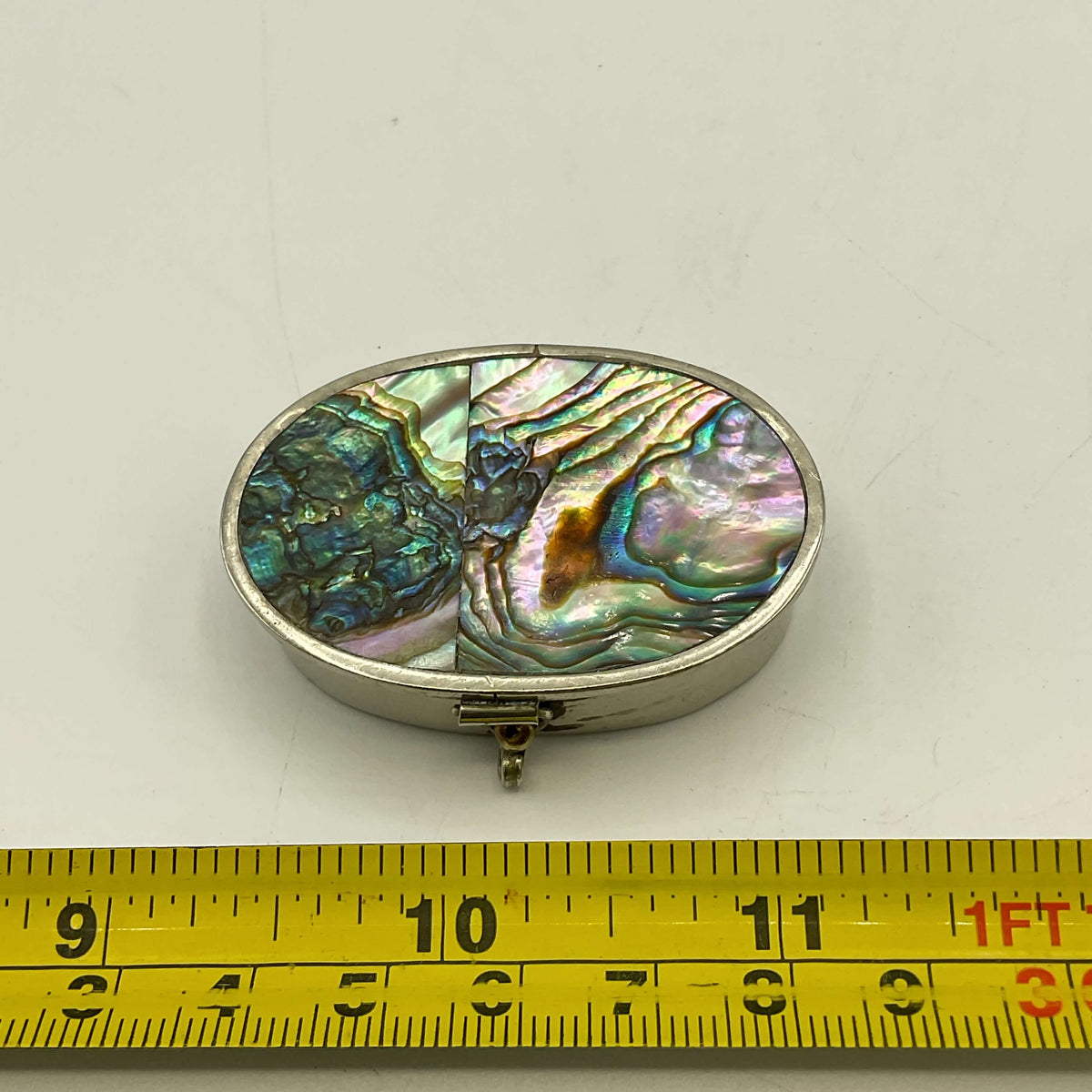 Mexican Abalone Shell Pill Box next to a tape measure for scale on a white surface