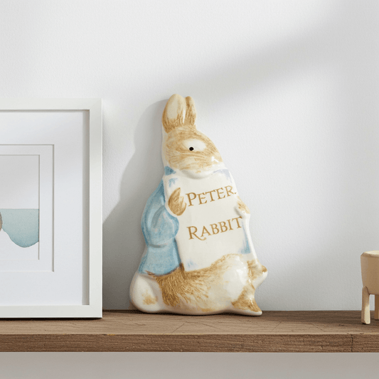 Decorative plaque shaped like a rabbit with 'Peter Rabbit' text on a shelf.