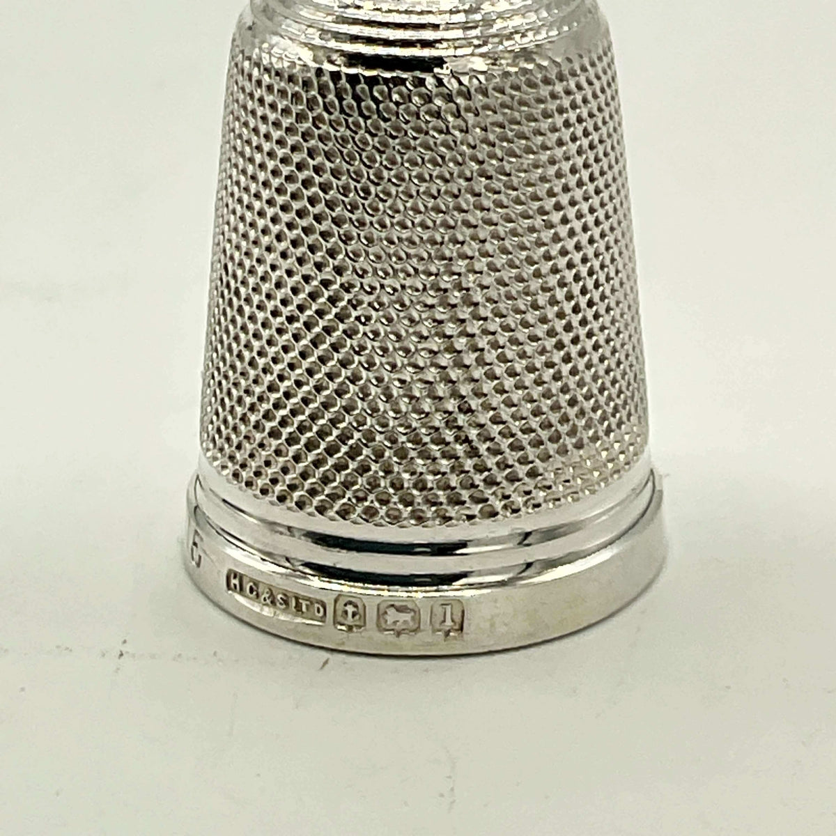 close up of hallmarks on silver thimble on white background