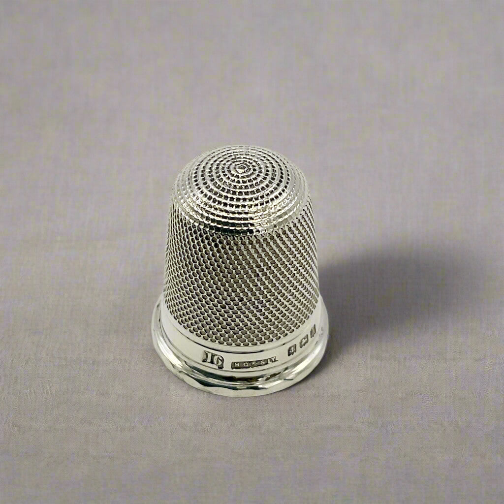 Silver thimble on a grey background