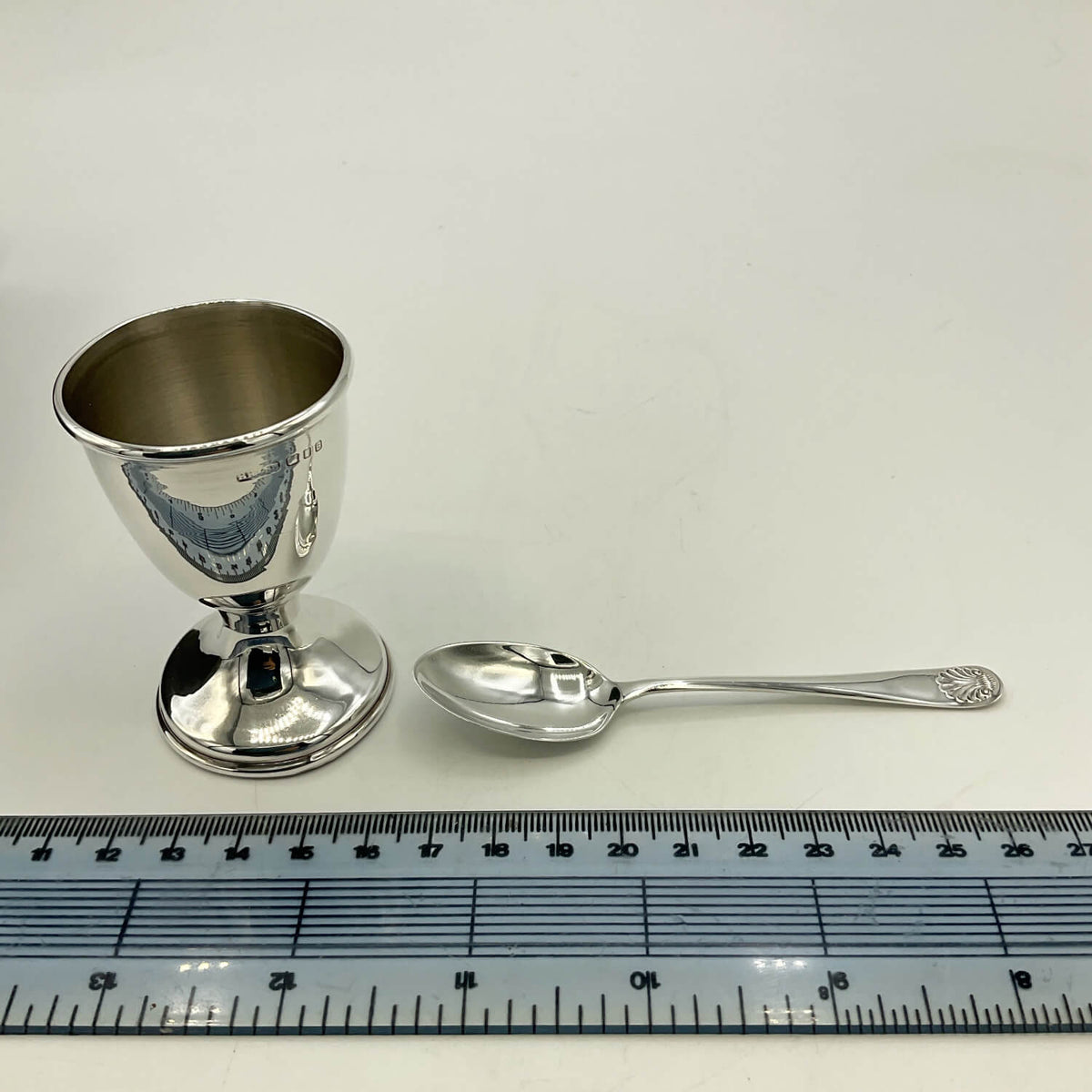 Sterling Silver Egg Cup and Spoon next to a ruler for scale on a white background
