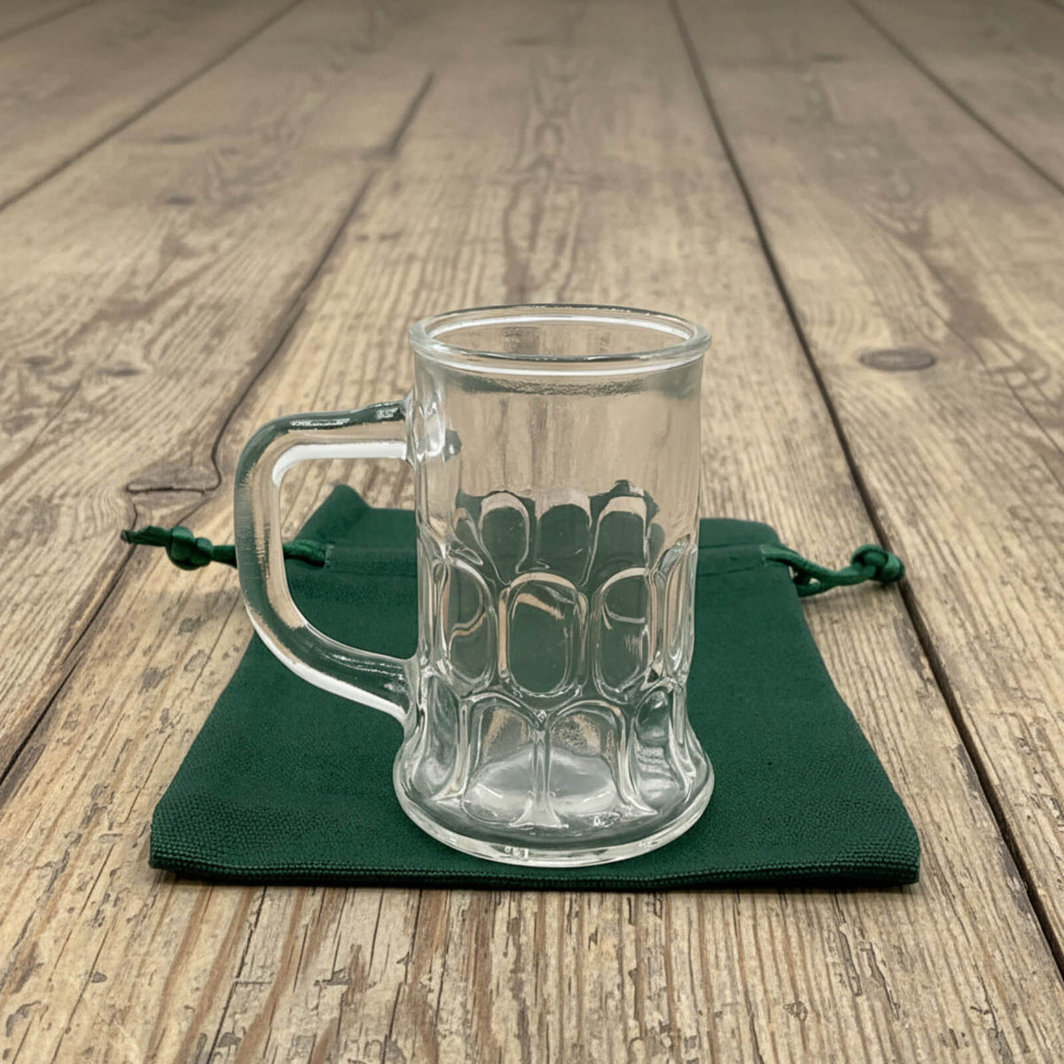 Clear glass mug with handle on a green cloth on a wooden surface