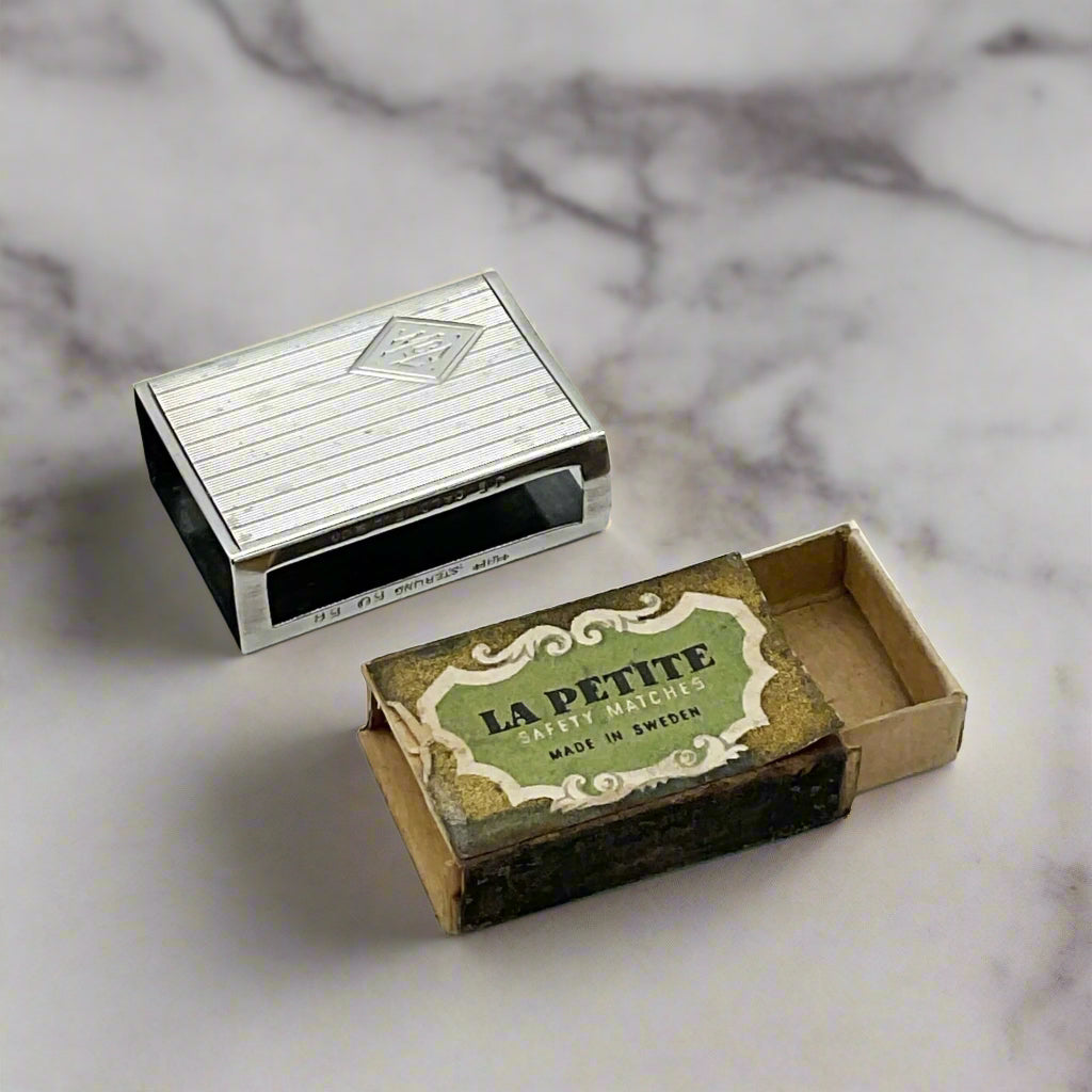 Silver matchbox and open matchbox with 'La Petite' branding on a marble surface