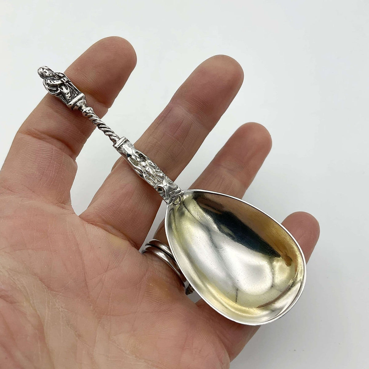 tea caddy spoon held in a hand with a white background