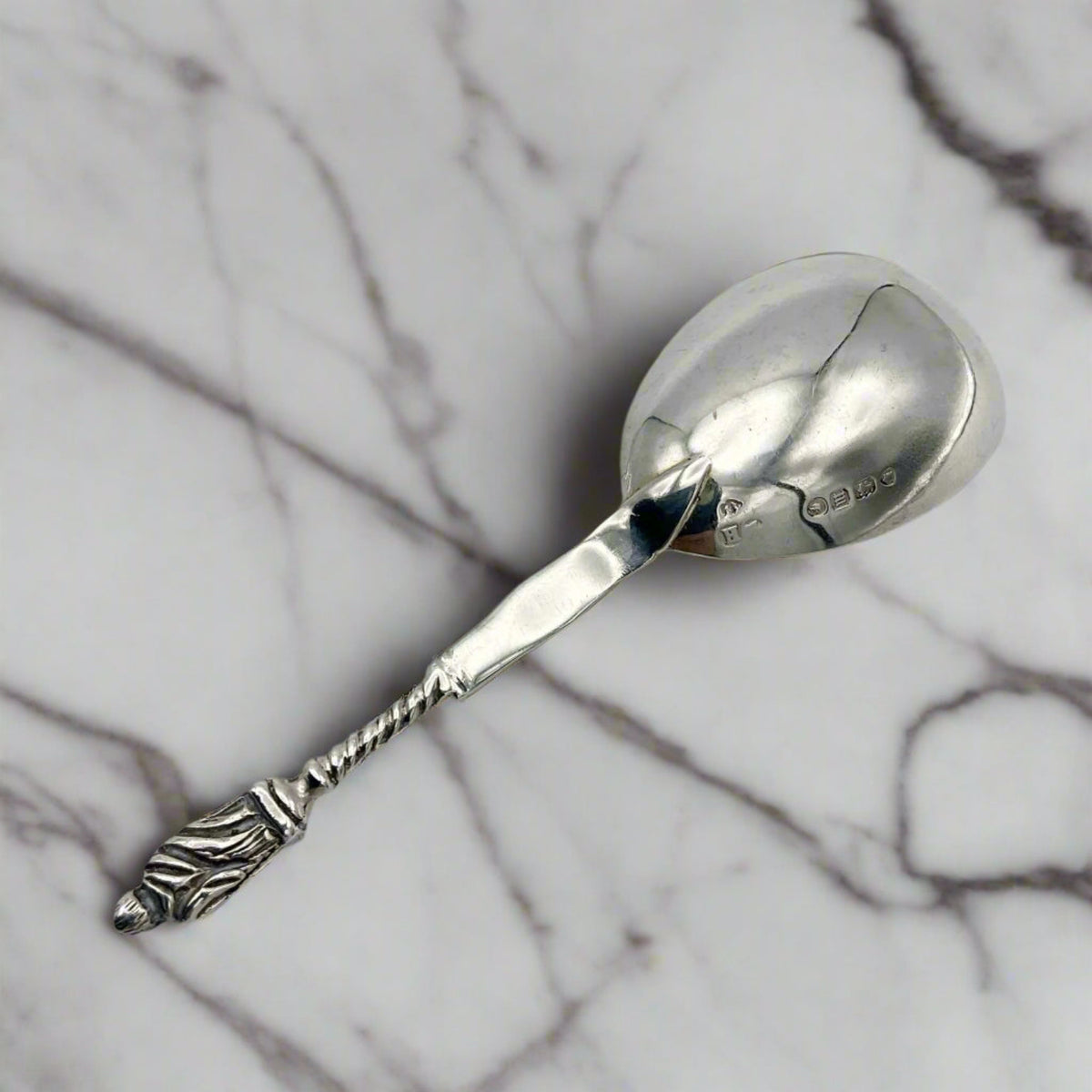 Back of silver caddy spoon on a marble surface