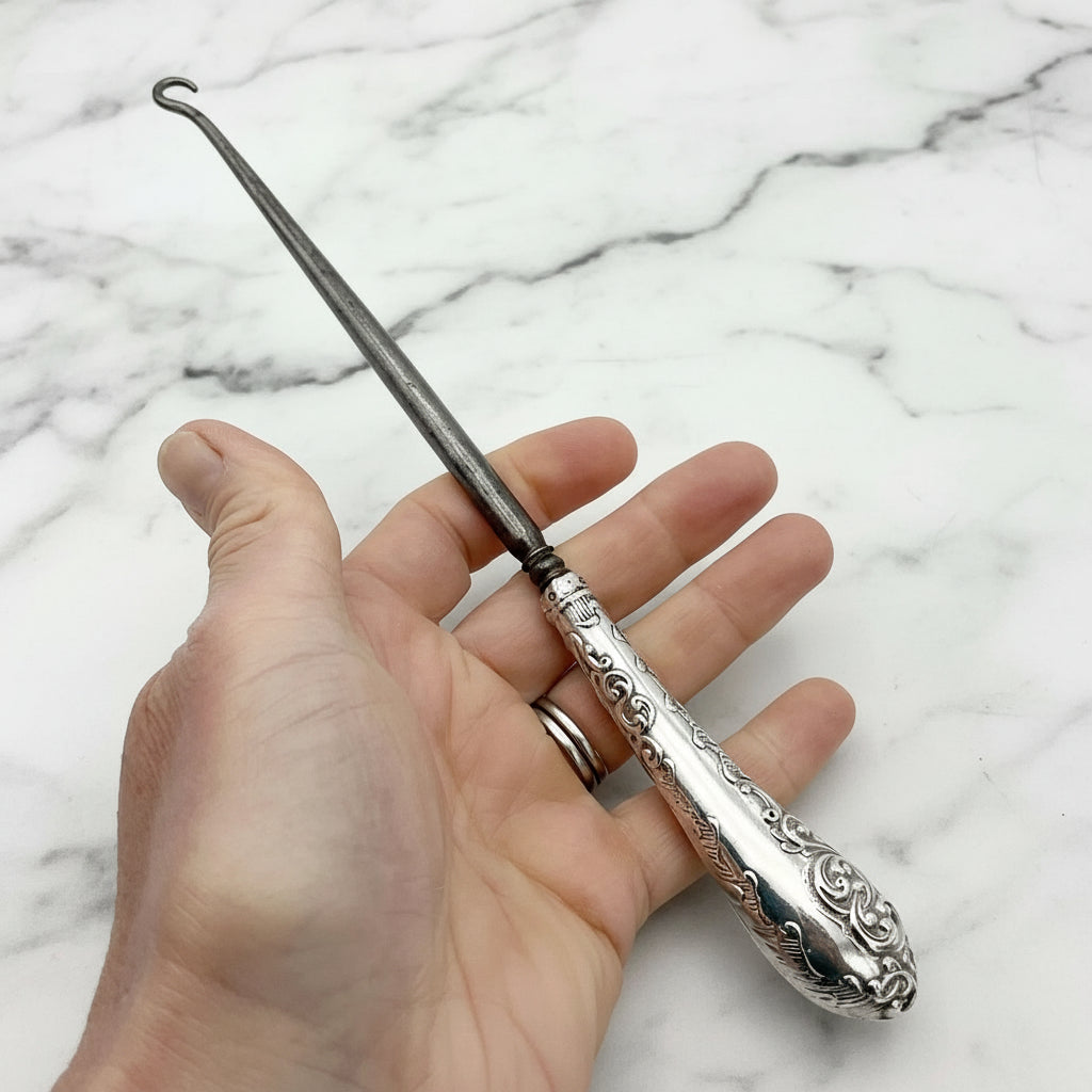 silver handled antique button hook being held in a hand