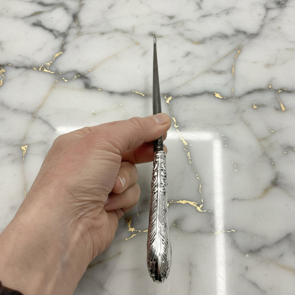 view of top of antique silver button hook in a hand