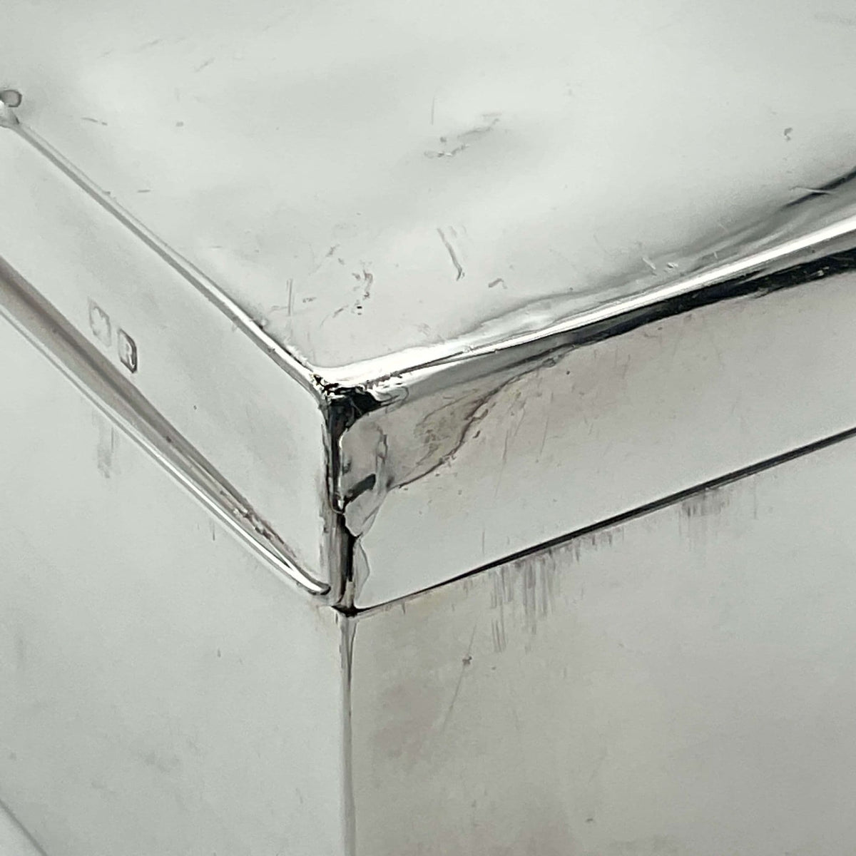Photo showing the corner of the silver cigarette box with a small tear to the corner