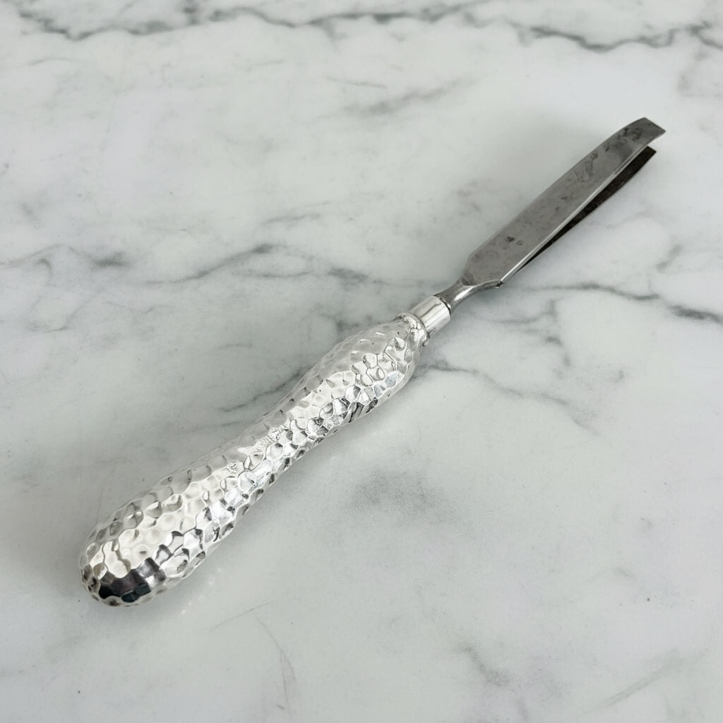 Metal tweezers with textured handle on a marble background