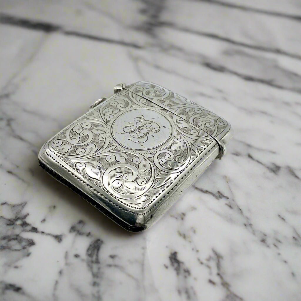 Decorative silver Vesta case with intricate designs on a marble surface