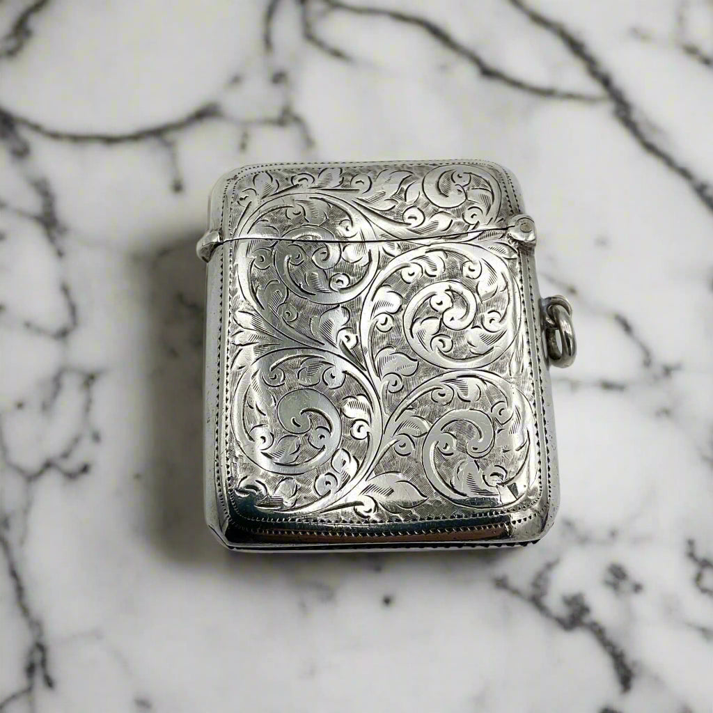 Back of silver Vesta case with art nouveau design on a marble worktop