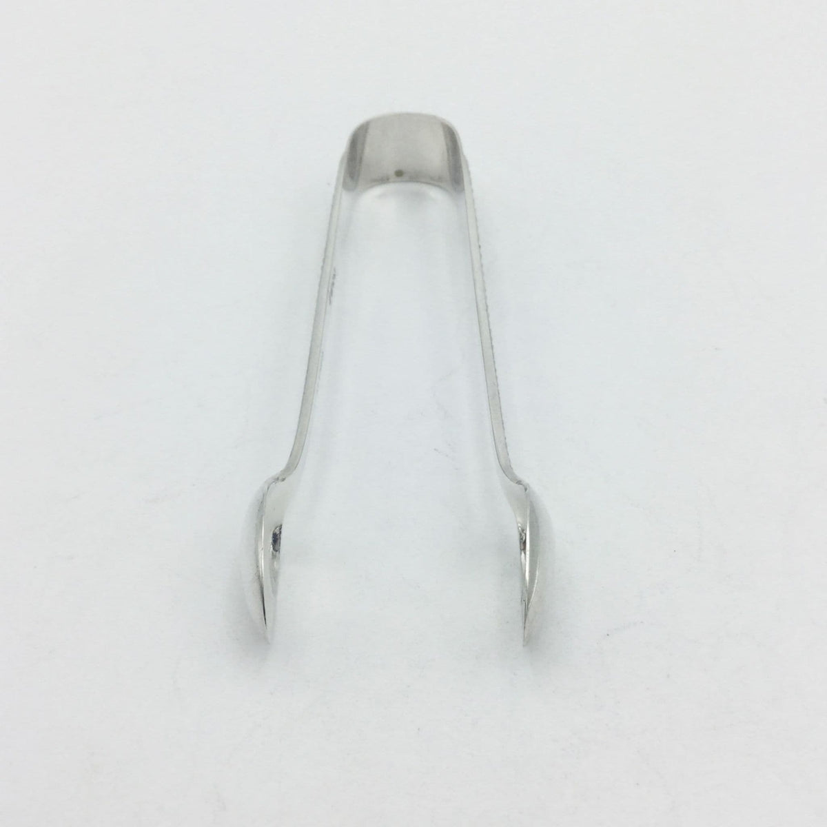 End of silver plated sugar tongs with the arms pointing towards the camera
