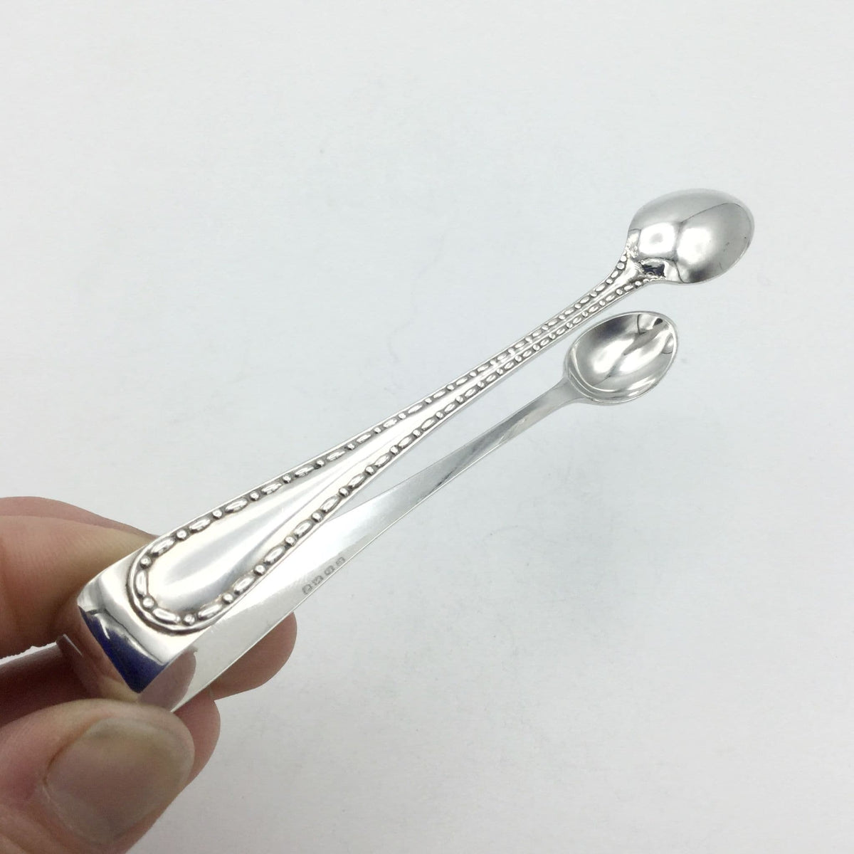 sugar tong arm with a dash pattern held by fingertips