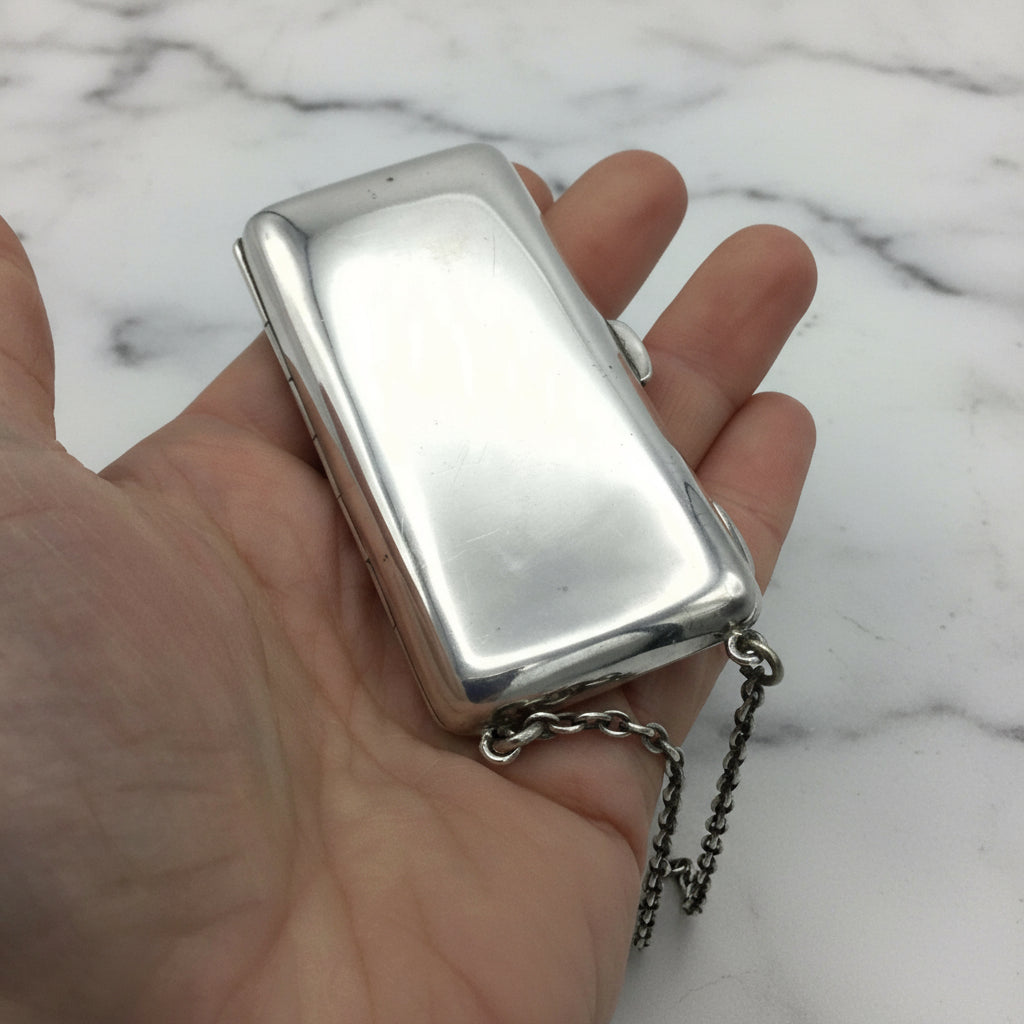 silver case with chain in a hand with a marble background