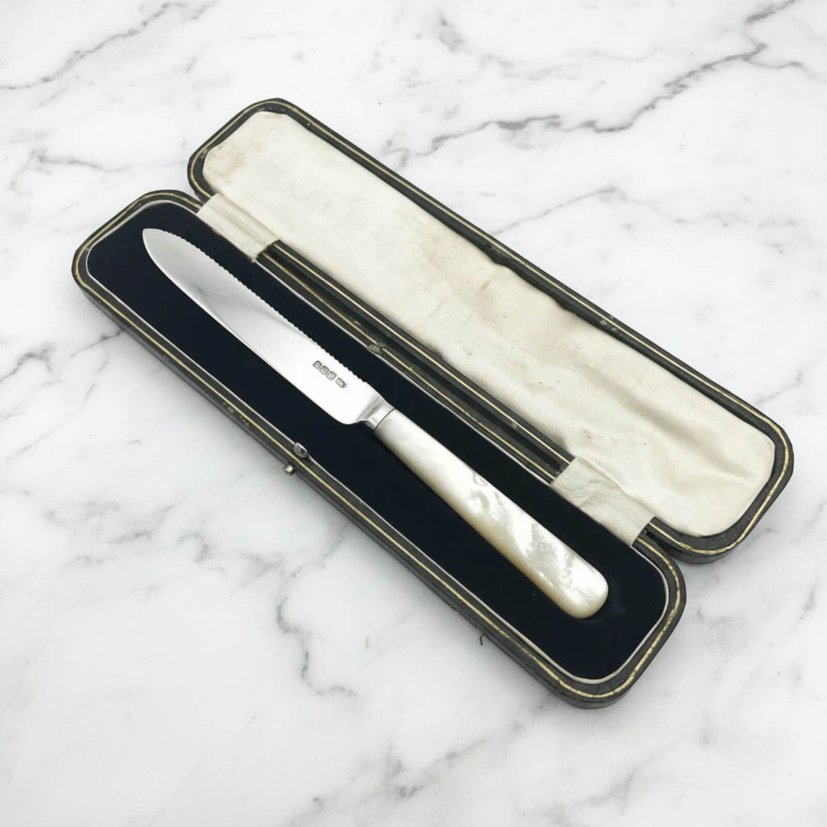 Knife with a decorative handle in an open case on a marble surface