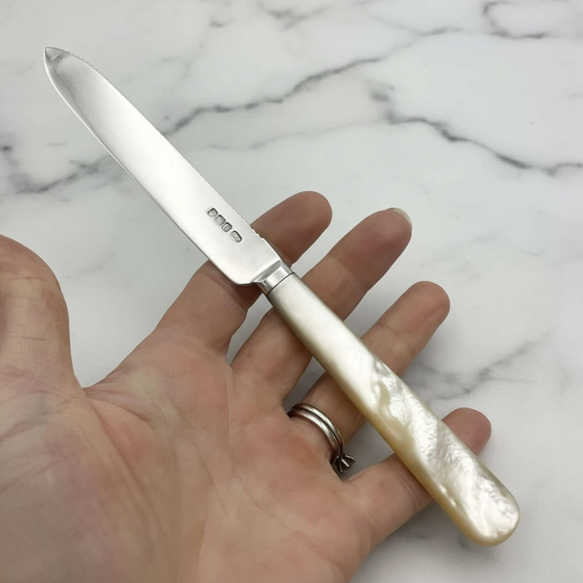 Knife with a decorative handle held in a hand on a marble background