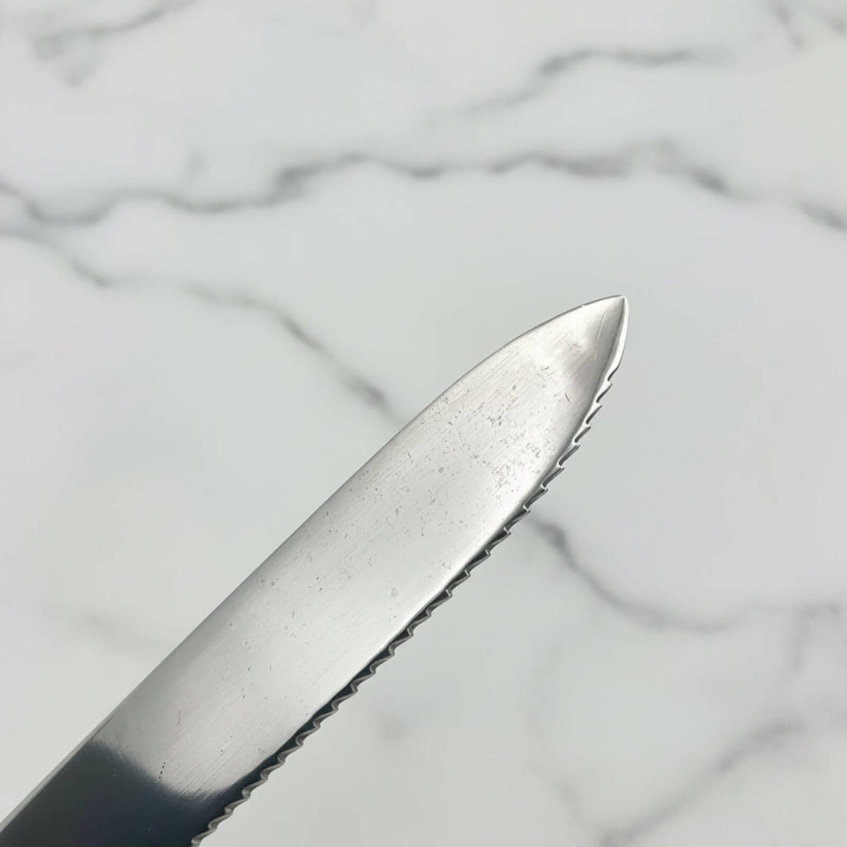 Close-up of a knife blade on a marble surface