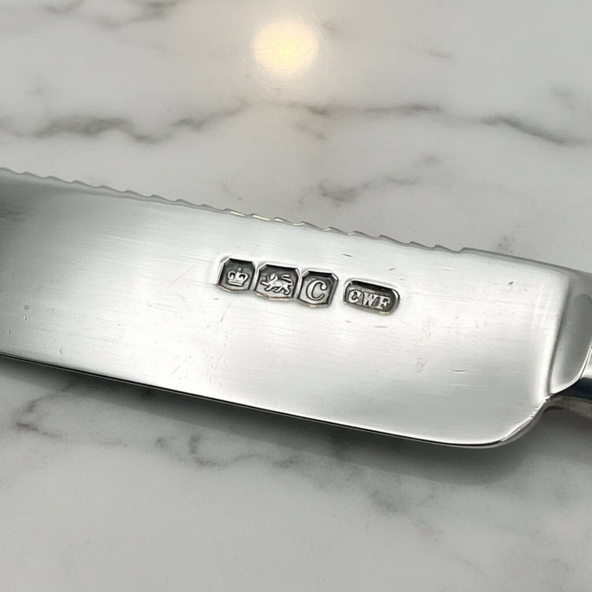 Silver knife with engraved hallmarks on a marble surface