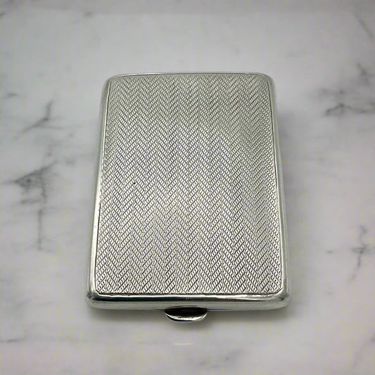 Antique sterling silver match case with a geometric pattern and a clasp on the front, displayed against a marble background 