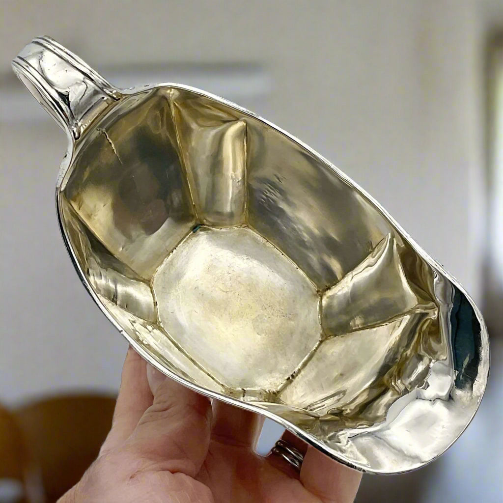 Inside of. Antique silver jug held in a hand on a dining room background