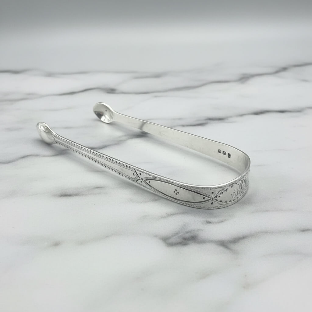 Silver sugar tongs on a marble surface