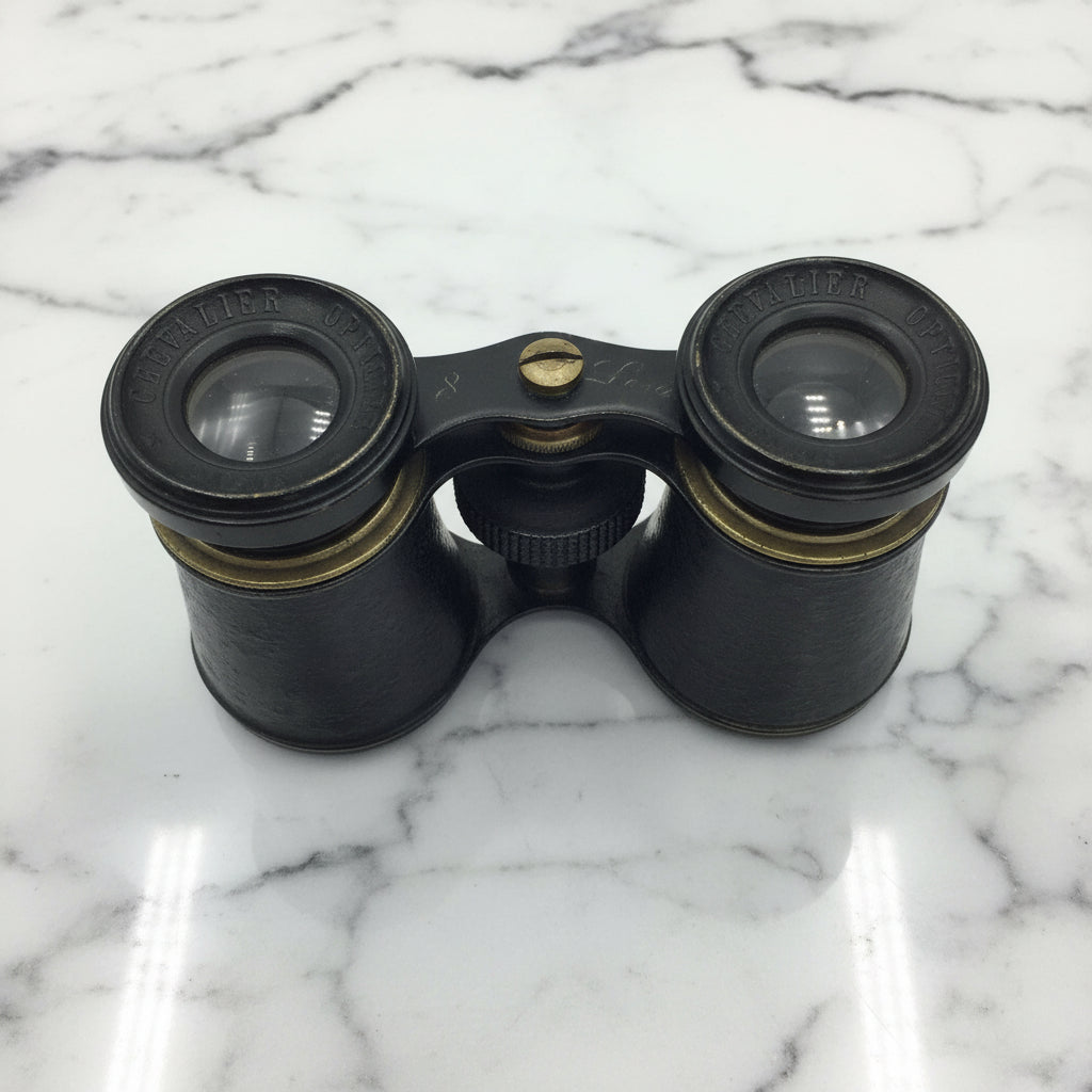 antique black binoculars on a marble surface