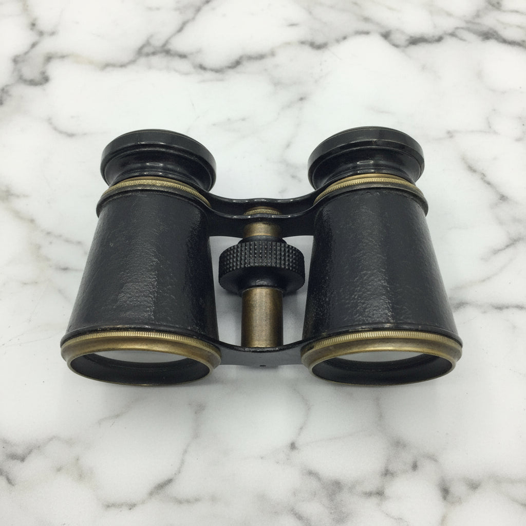 antique black binoculars on a marble surface
