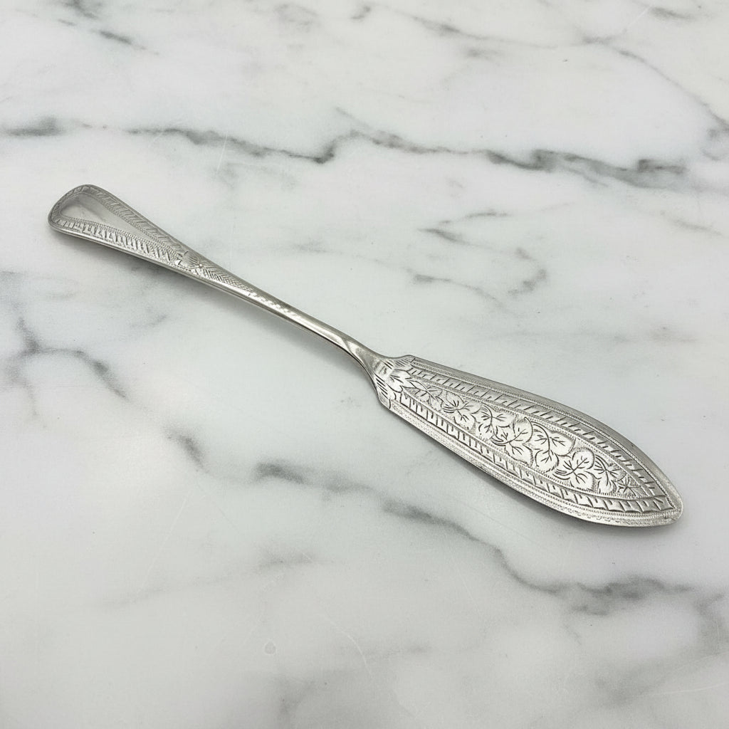 Antique silver plated butter knife with ornate design and EP stamped on the back of the handle, showing some wear on a marble surface