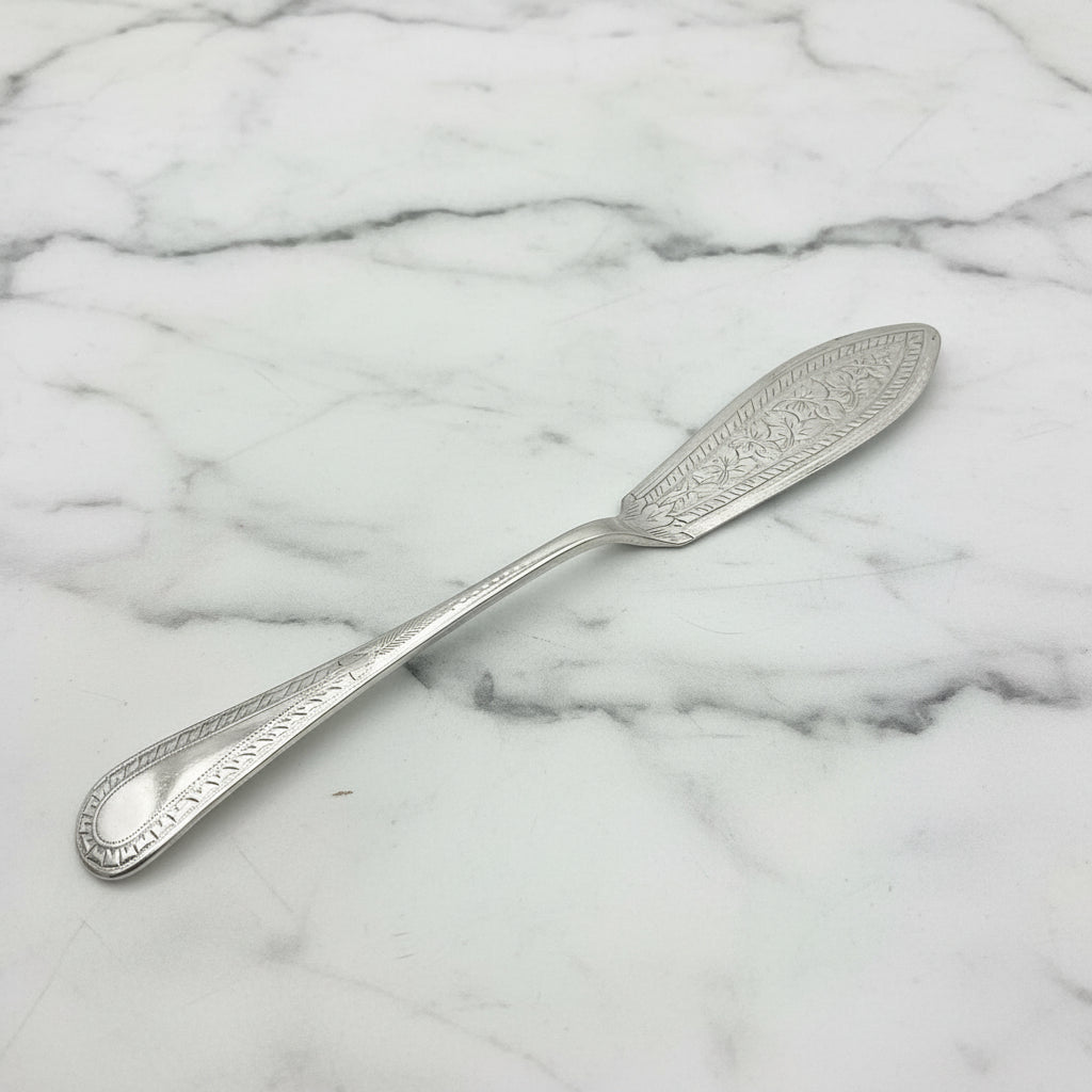 Decorative silver butter knife on a marble surface