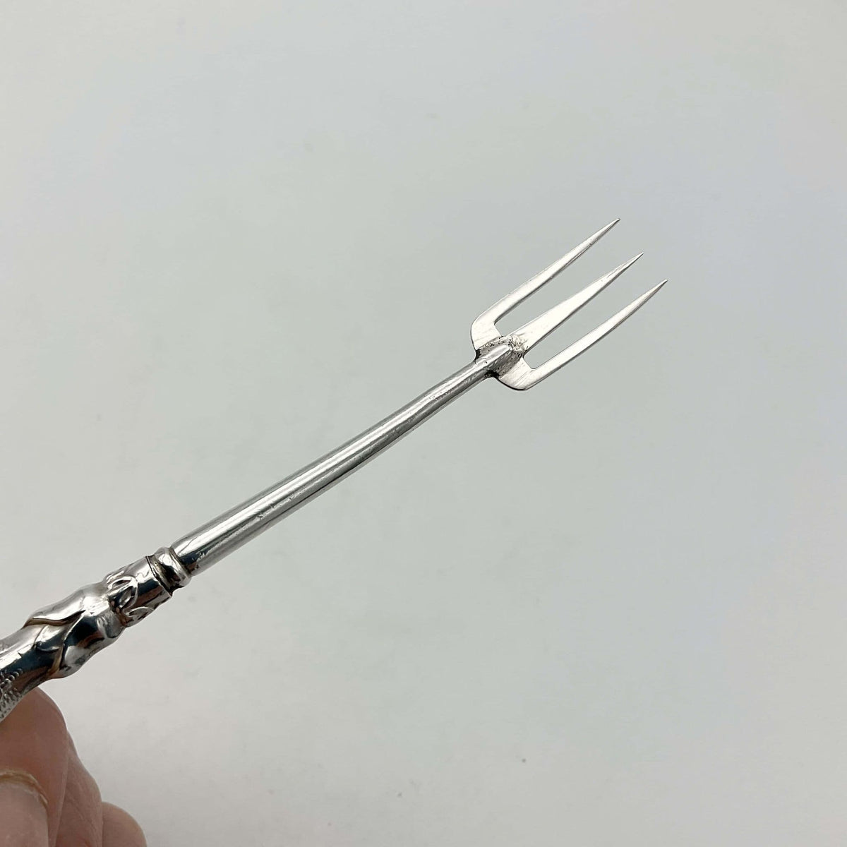 Antique silver plated pickle fork with an ornate handle 